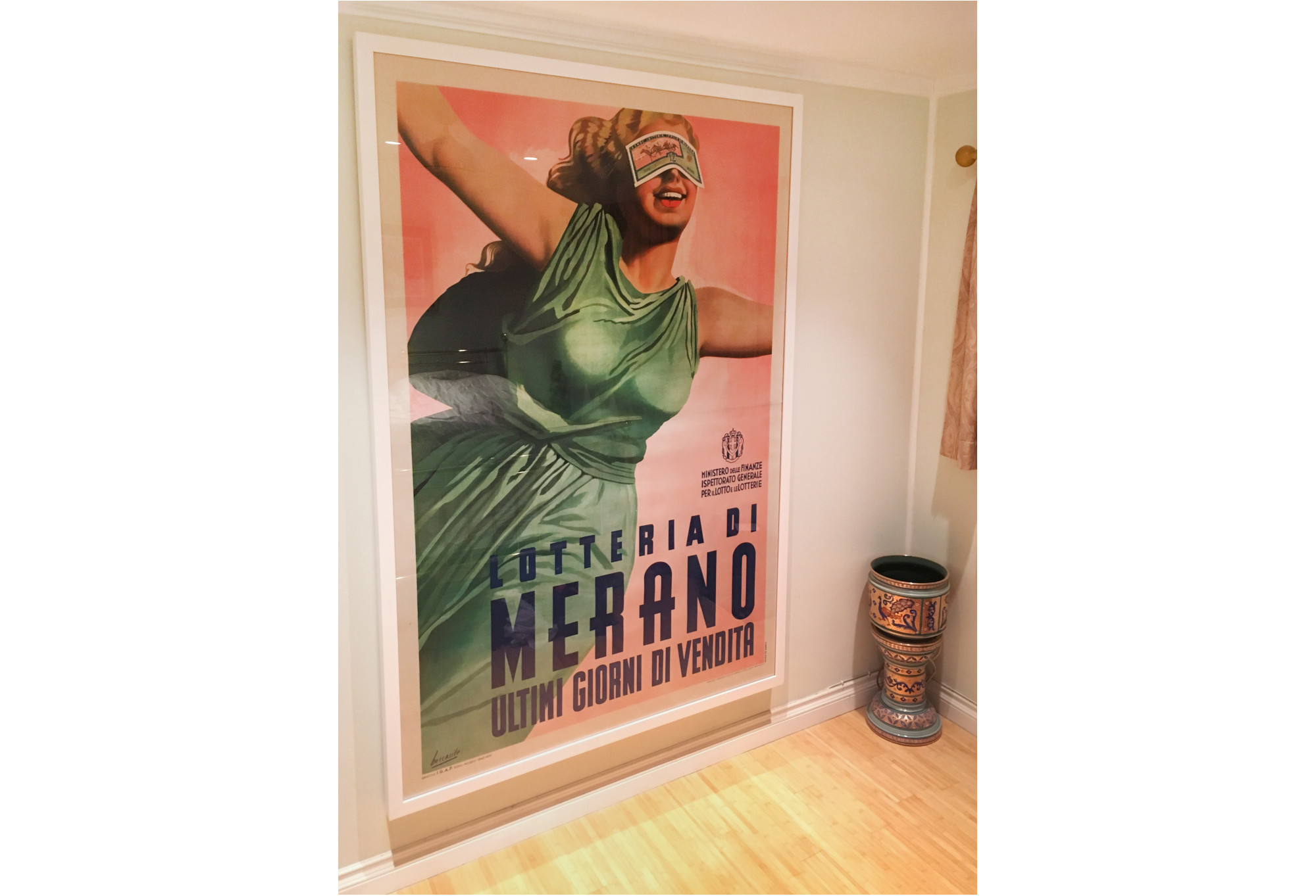 large framed poster in hallway with blindfolded woman in green dress; pink, green, yellow, white